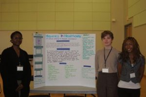 Three students standing next to a tri-fold panel used to present their ideas at the Student Health Literacy Conference.